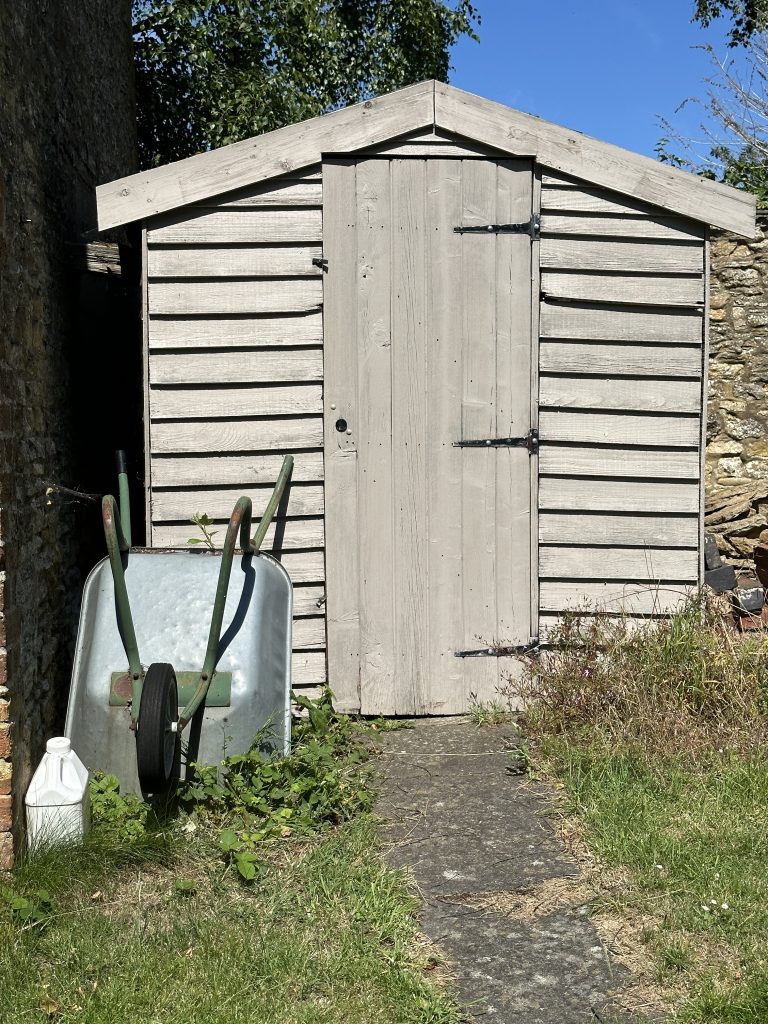 Brouette devant un abri de jardin en bois dans un jardin