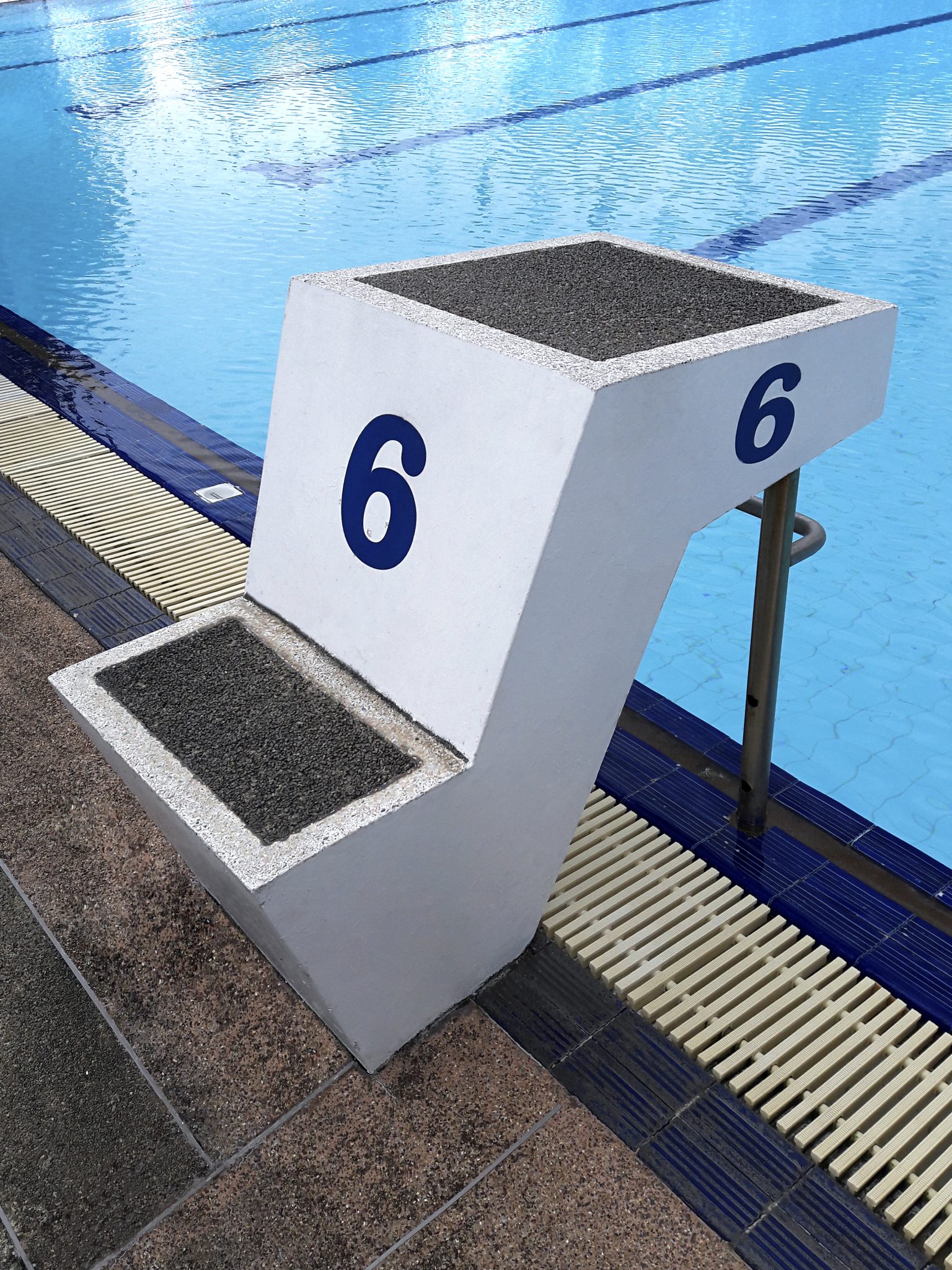 Vague d'eau bleue dans une piscine refletant la lumière du soleil sur des carreaux en céramique bleus, illustrant un environnement de piscine.